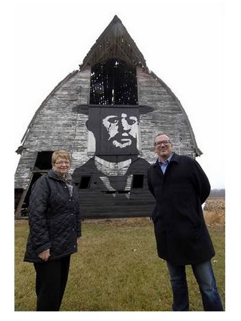Joan Peterson, left, of Clive, and her son, Curt Peterson of Des Moines, stand in front of their barn, upon which they painted a portrait of Henri de Toulouse-Lautrec. Image captured from Miami Herald. Original photo by Hans Madsen.