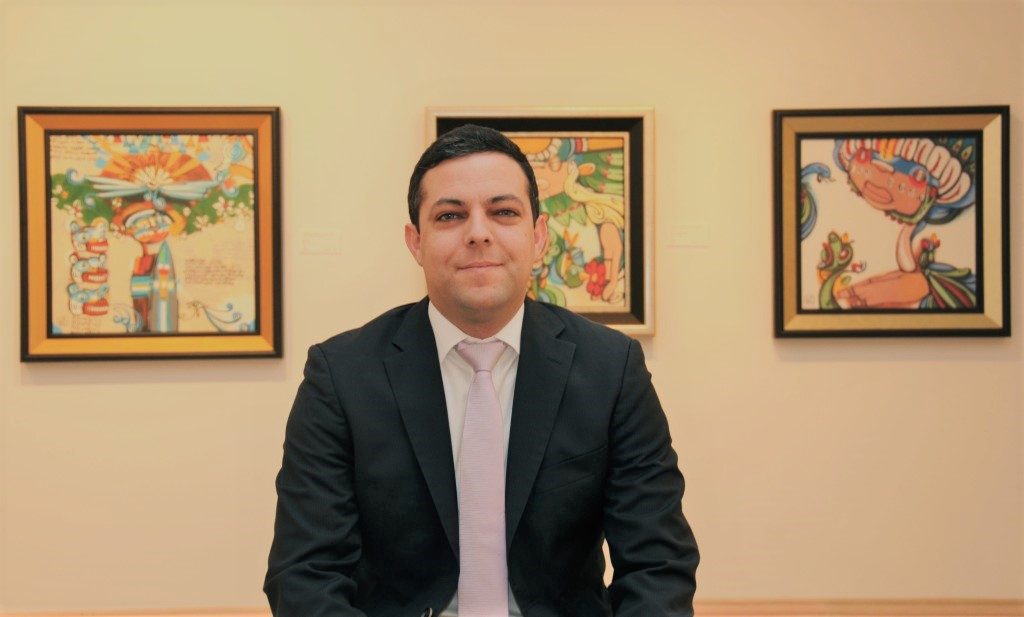 Auctioneer standing in front of the artwork he is selling