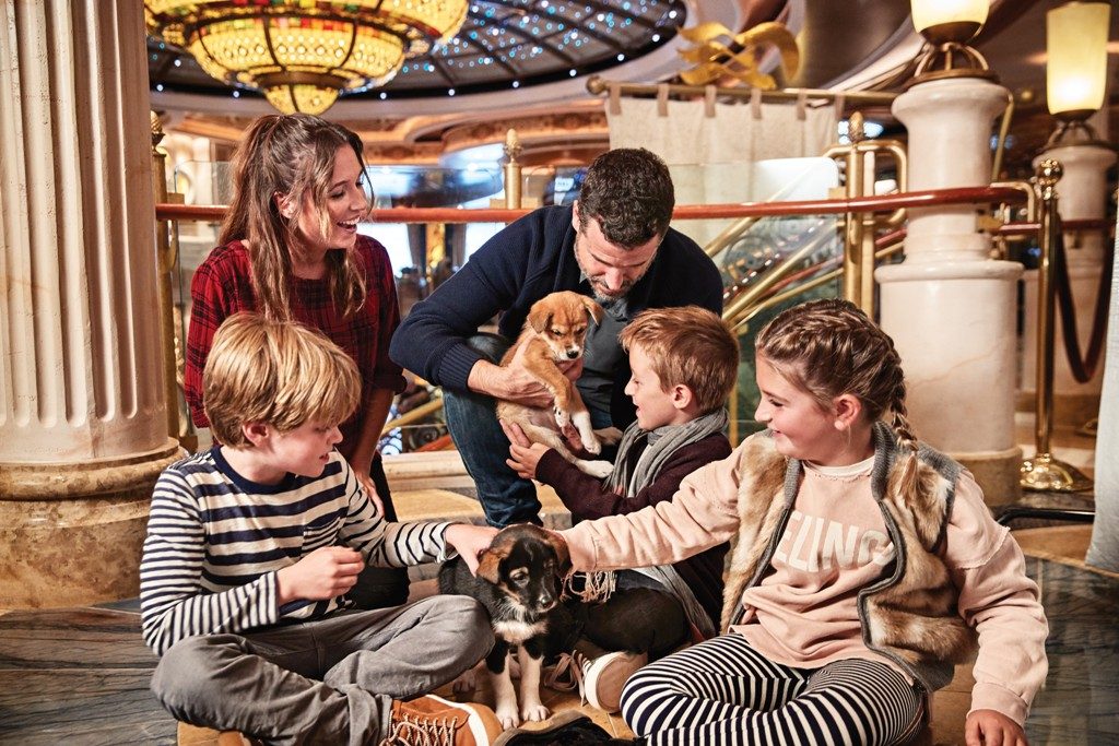 Family playing with sled dog puppies.