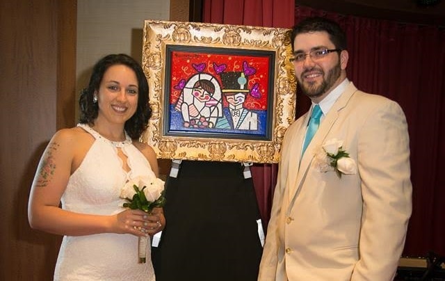 Carolyn and Christopher pose with their new Romero Britto painting at their cruise ship wedding.