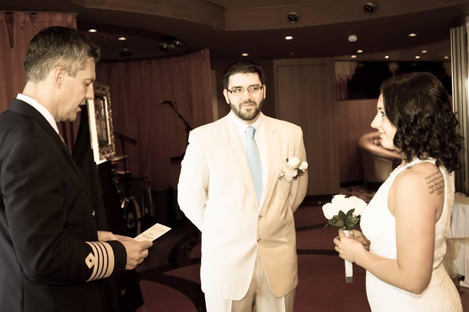 Carolyn and Christopher getting married, next to their new Britto painting, at their cruise ship wedding.