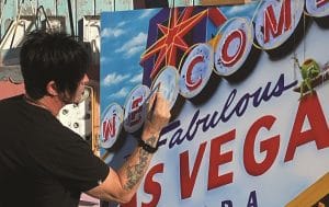 Michael Godard paints one of his olives (and a tribute to his hometown) in Las Vegas' Neon Museum.