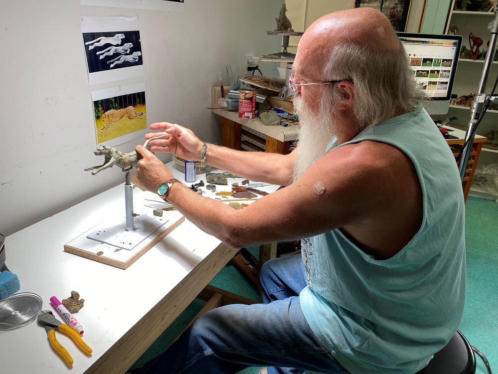 Lopez manipulates clay around a wire base for a new sculpture.