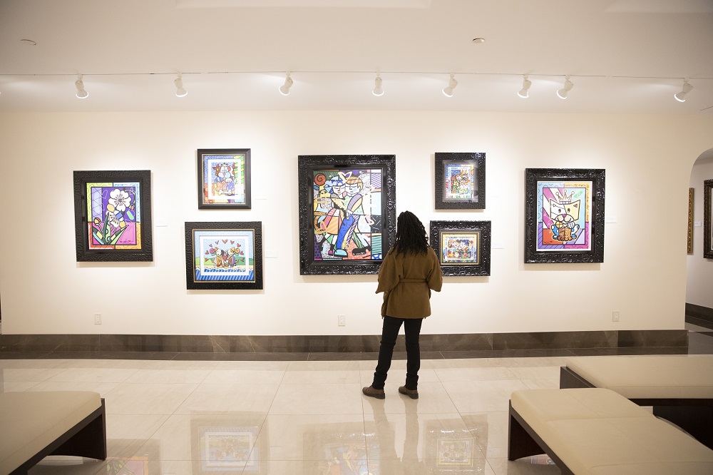 A visitor browses a wall of works by artist Romero Britto in Park West Museum's downstairs gallery space.