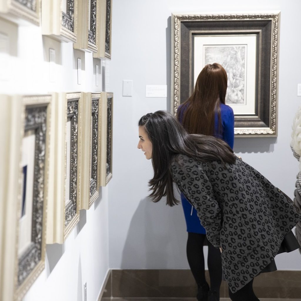 A curious patron takes an up-close look at an etching by Rembrandt van Rijn.