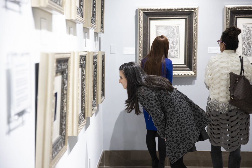 A curious patron takes an up-close look at an etching by Rembrandt van Rijn.