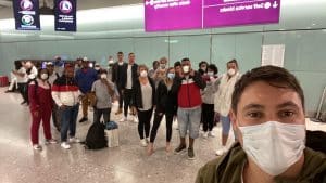 Auctioneer Jared Hamer poses with stranded cruise ship workers at London's Gatwick airport.