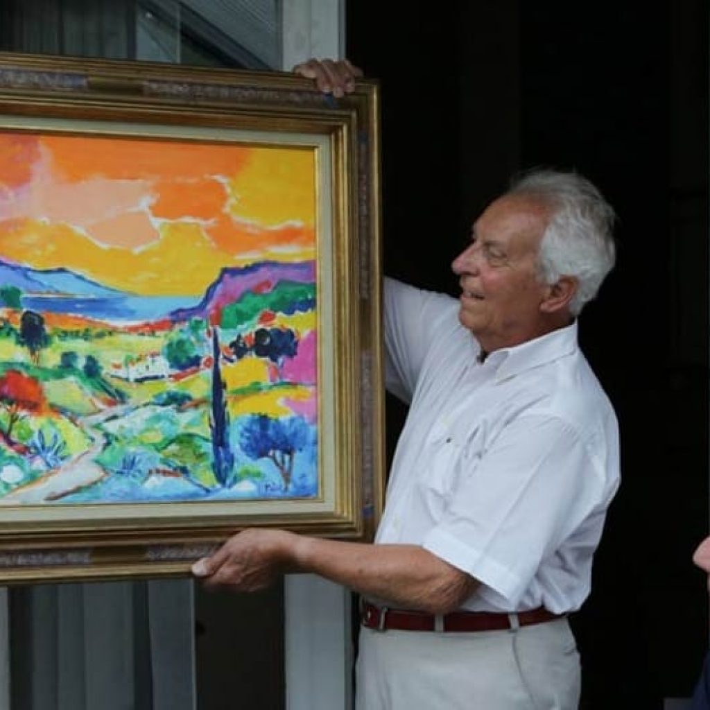 Jean-Claude Picot proudly shows one of his paintings at his home in France.