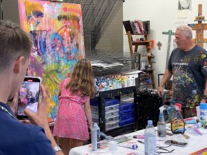 Tim Yanke mentors a young art enthusiast as she works on their collaborative painting in Yanke's studio.