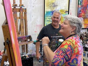 Artist Tim Yanke proudly watches a collector add her own contribution to a work of art in his studio.
