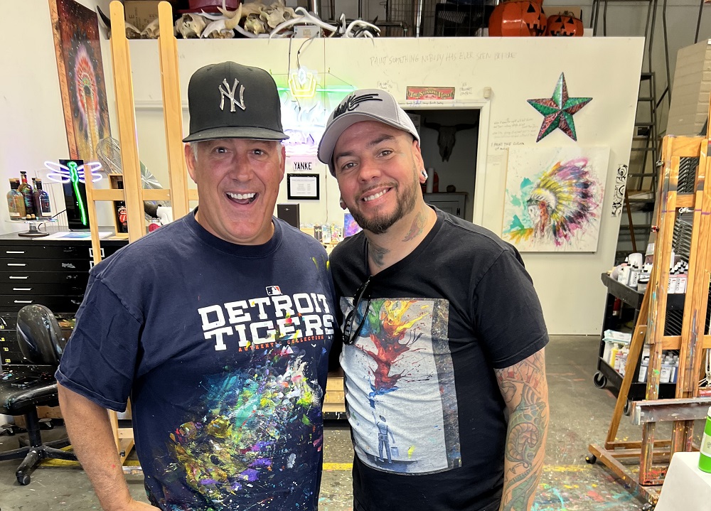 Two artists, covered in paint, at the end of a successful collaboration
